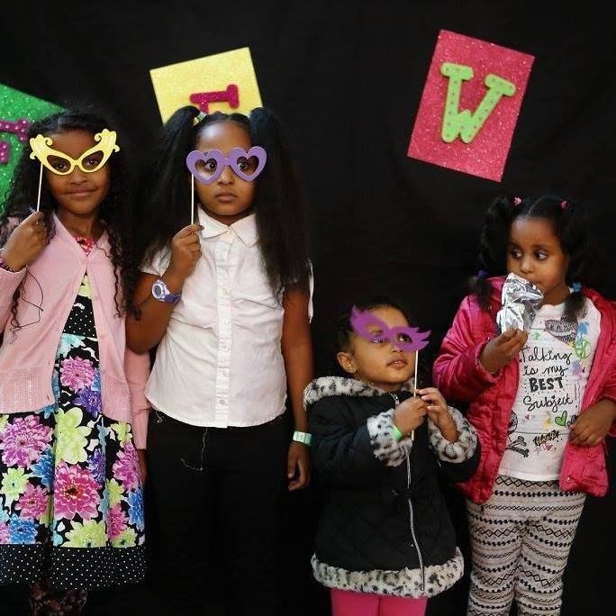 A group of young girls standing in front of a sign that has the letter w on it