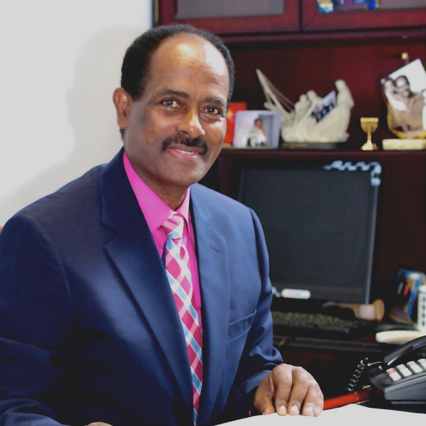 A man in a suit and tie is sitting at a desk