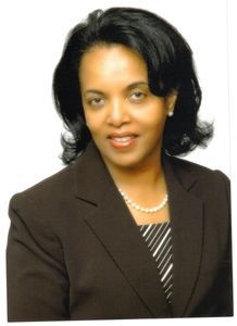 A woman wearing a brown jacket and a pearl necklace