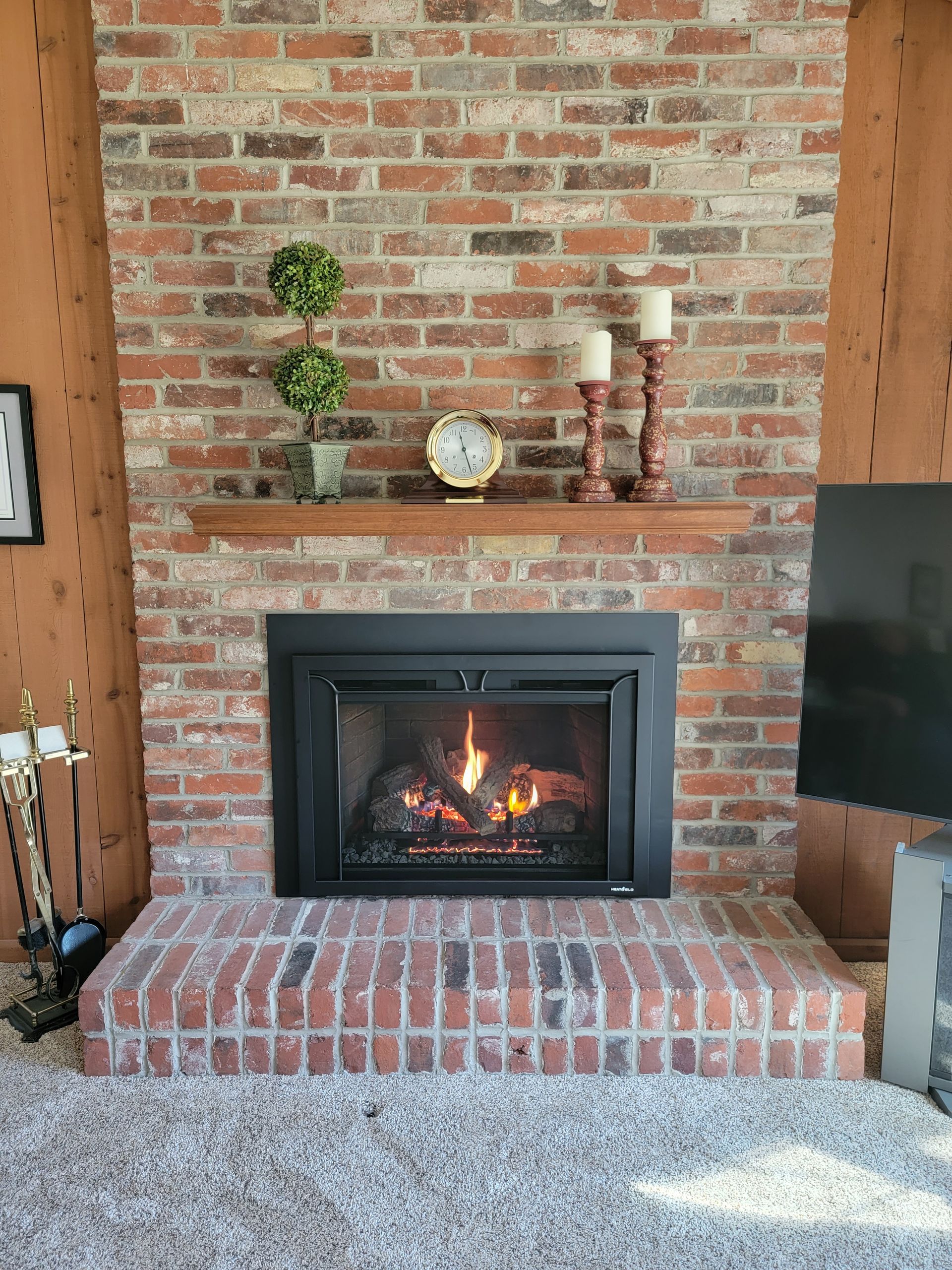 A living room with a fireplace and a clock on the mantle.