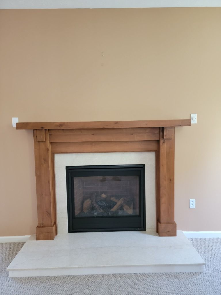 A fireplace with a wooden mantle in a living room.