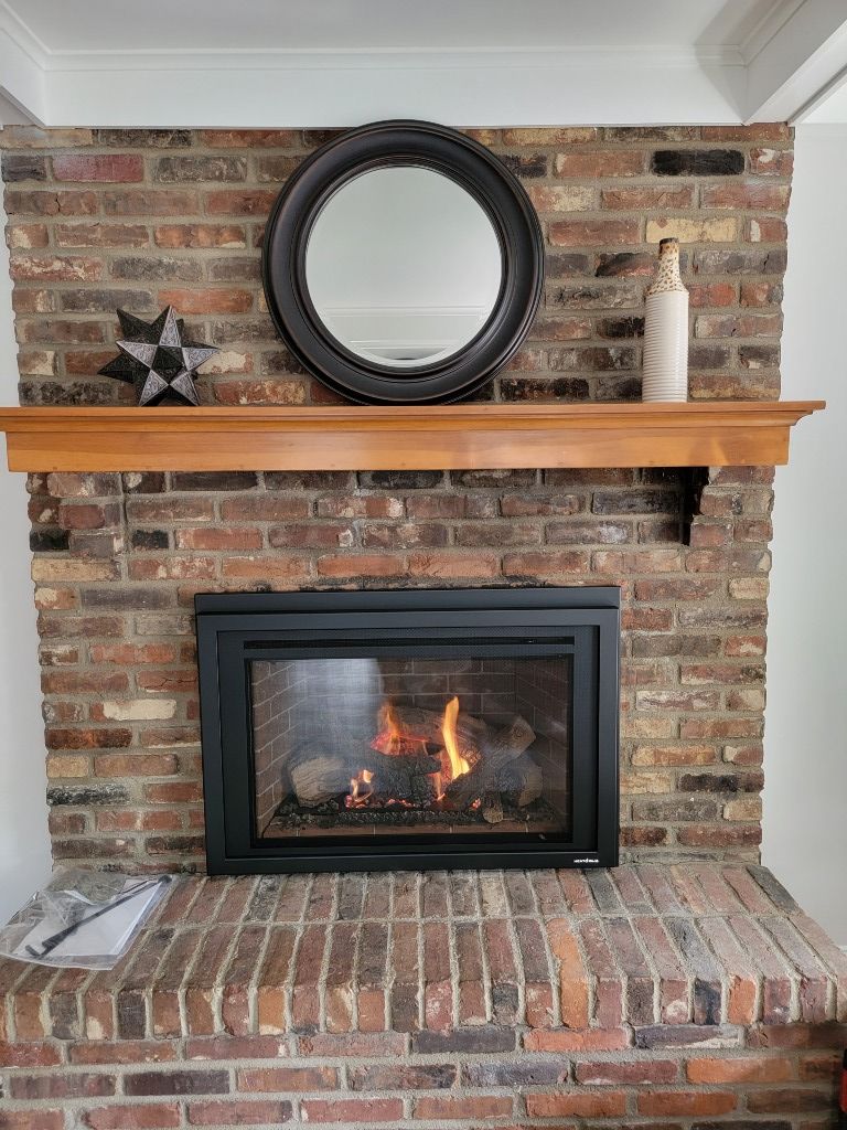 A fireplace with a mirror above it and a brick wall.