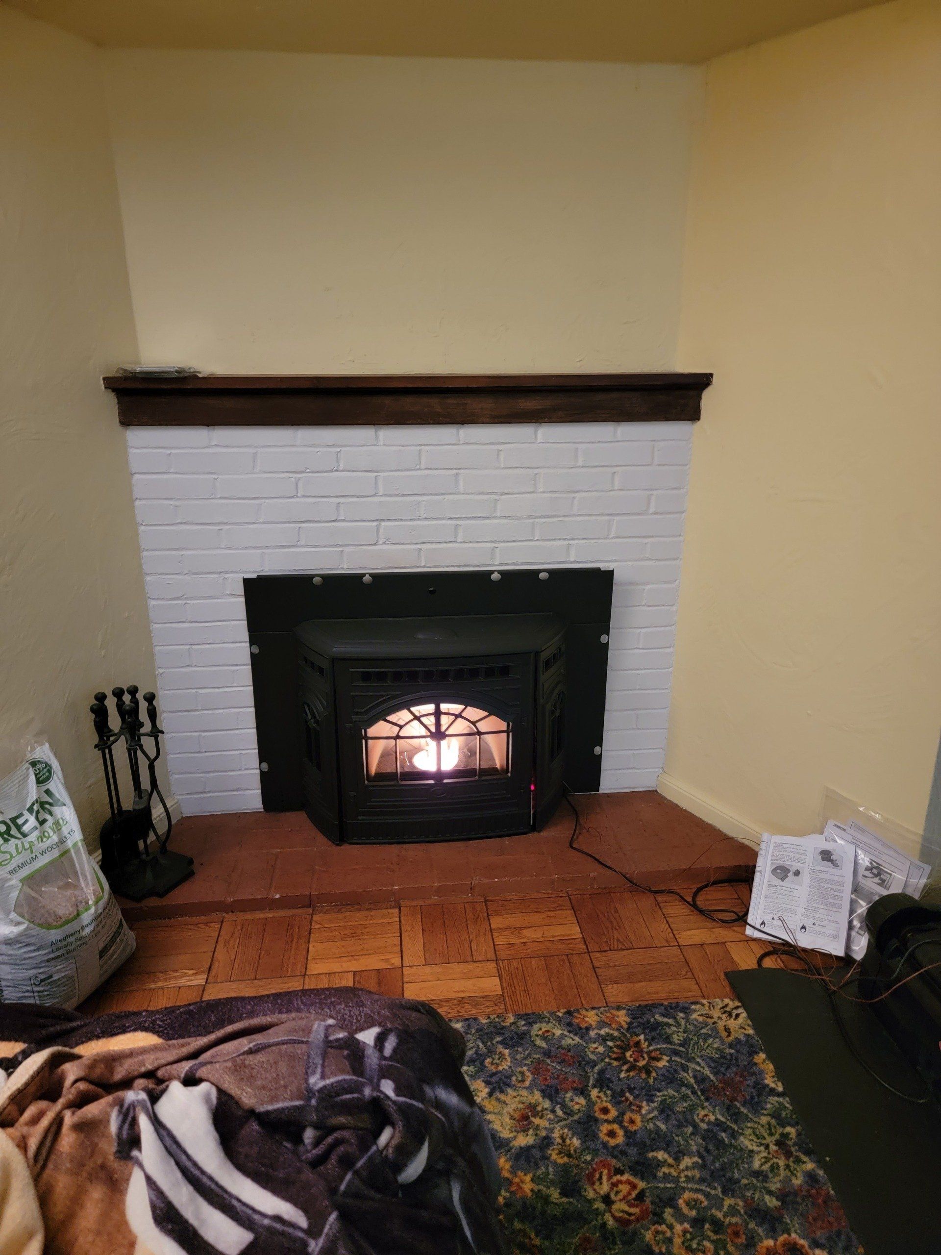 A wood stove is sitting in a fireplace in a living room.