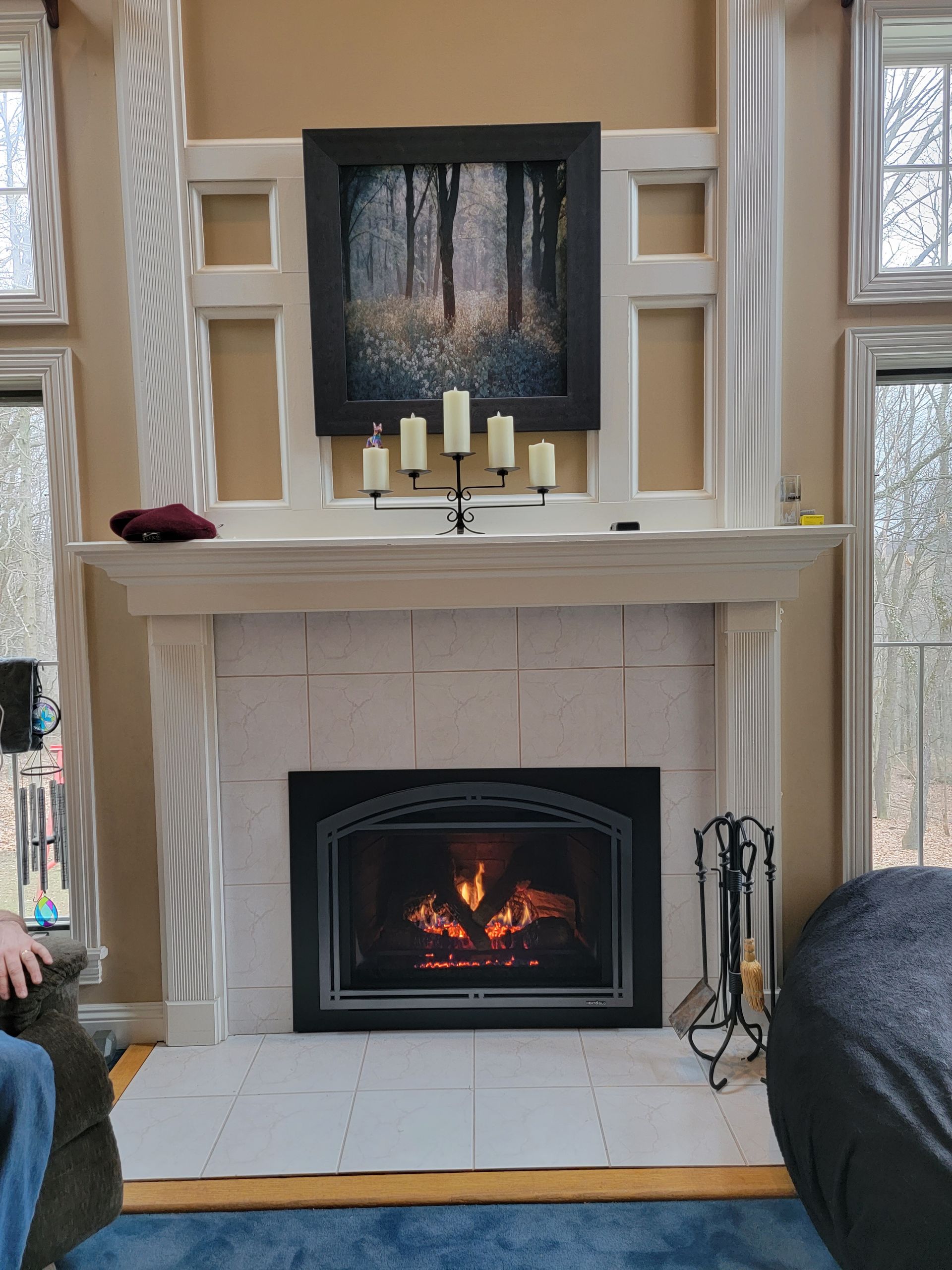 A living room with a fireplace and a painting on the mantle.