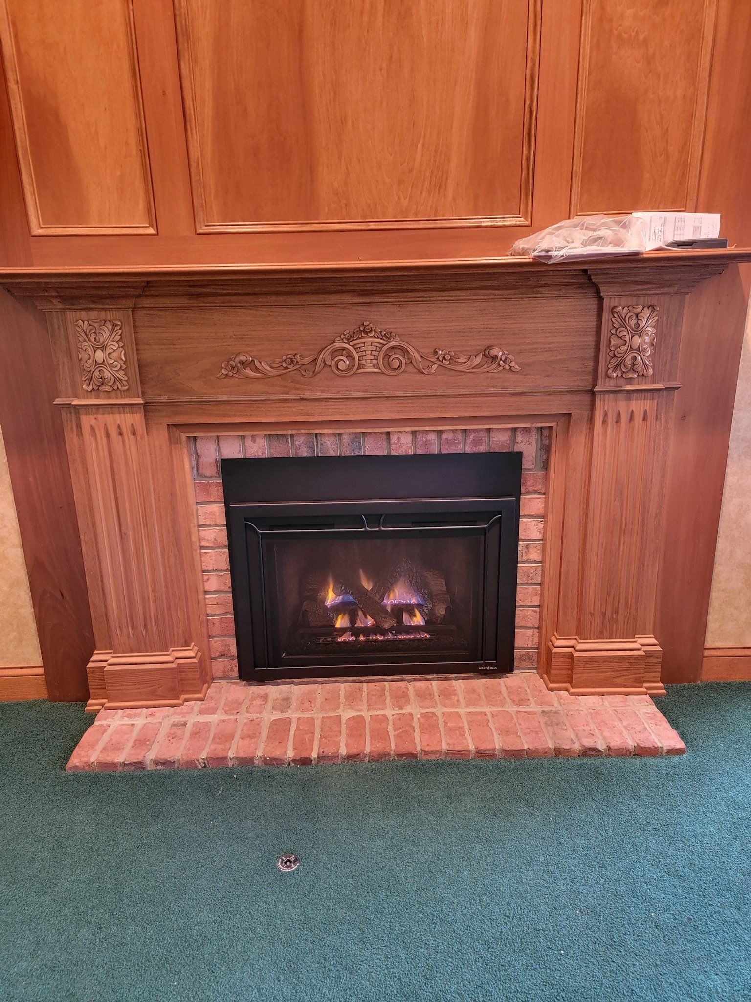 A brick fireplace with a wooden mantle in a living room.