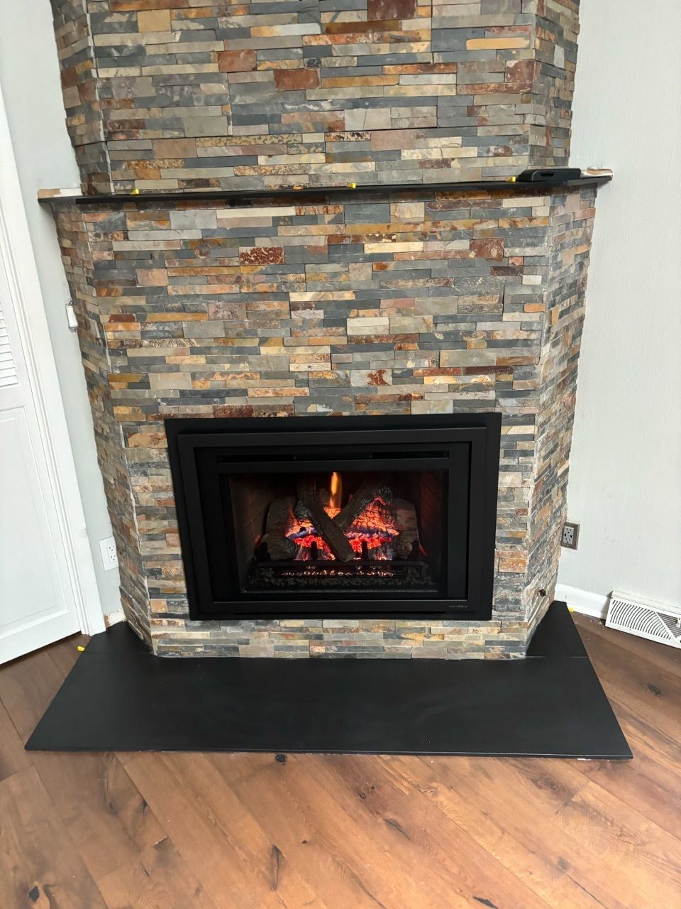 A fireplace with a brick wall and a wooden floor in a living room.