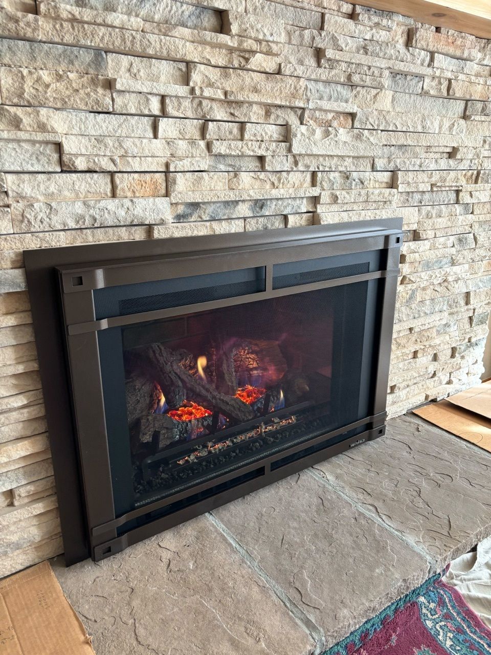 A fireplace is sitting in a living room next to a brick wall.