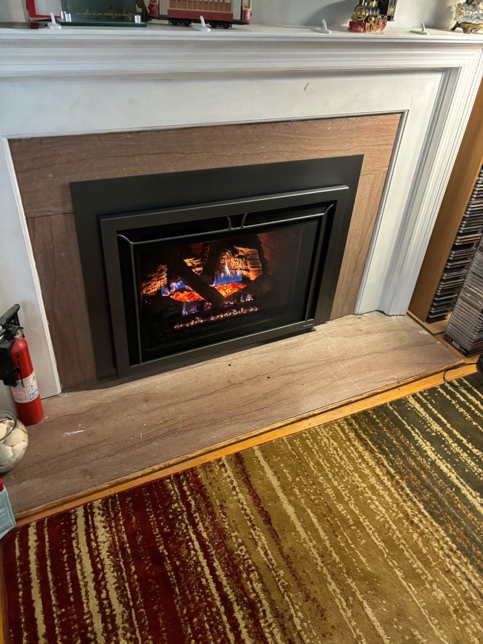 A fireplace in a living room with a rug and a fire extinguisher.