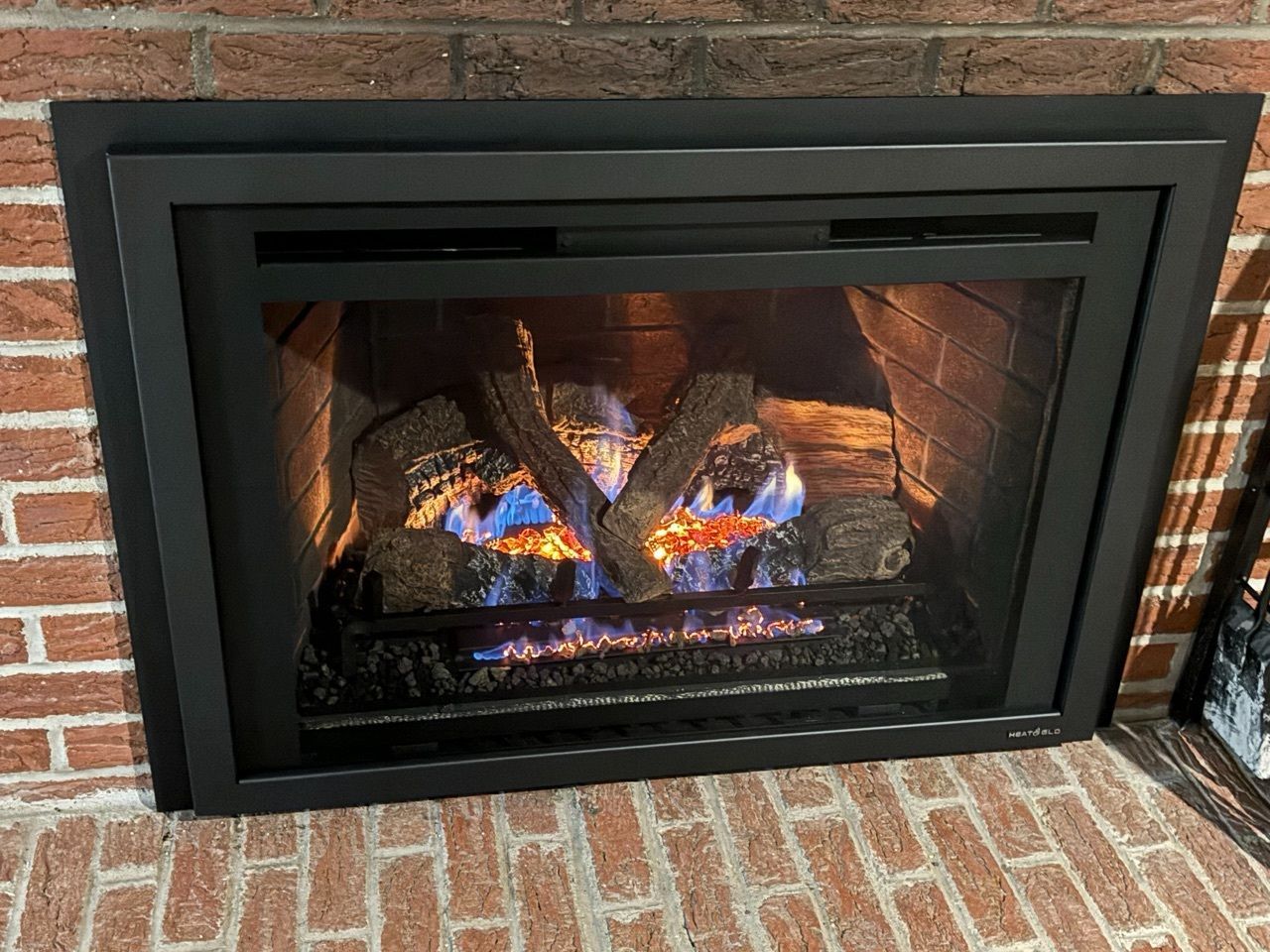 A gas fireplace is sitting on top of a brick wall.