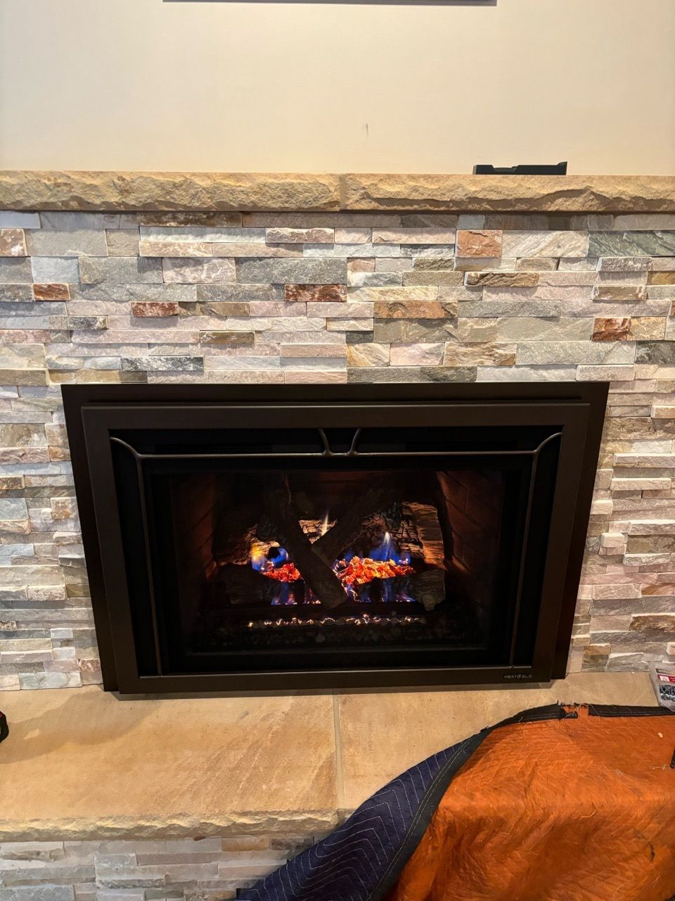 A fireplace with a brick wall and a blanket on the floor.