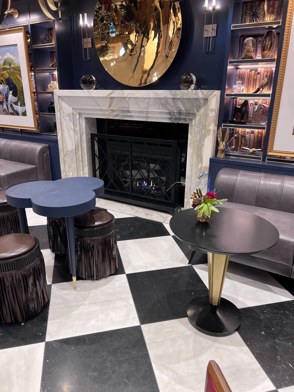A living room with a fireplace , tables , stools and a checkered floor.