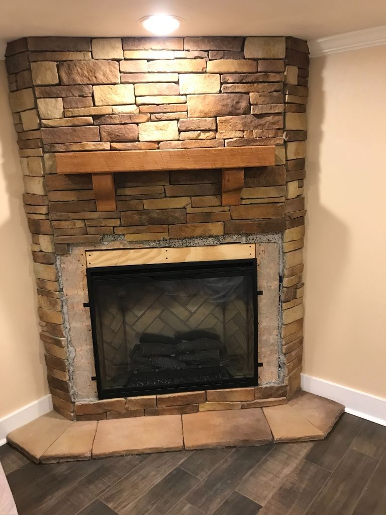 A fireplace with a brick wall and a wooden mantle