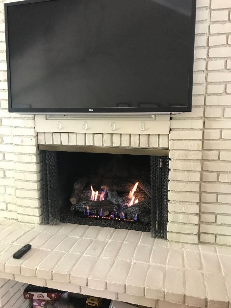 A fireplace with a flat screen tv mounted above it.
