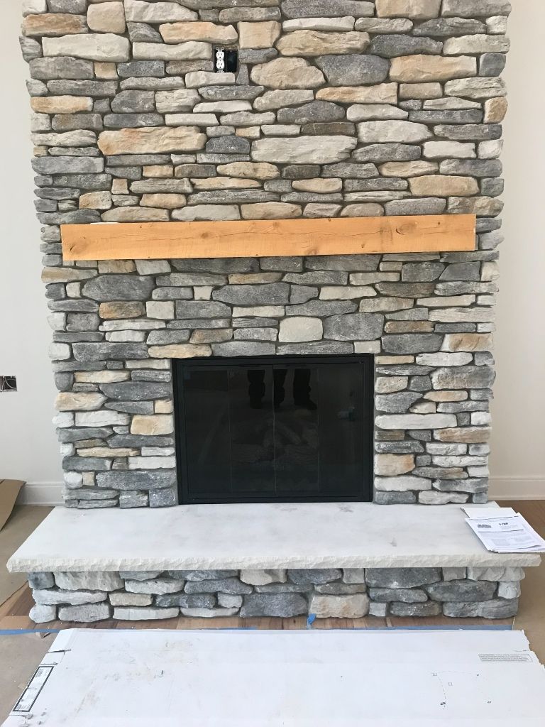 A stone fireplace with a wooden mantle in a living room.