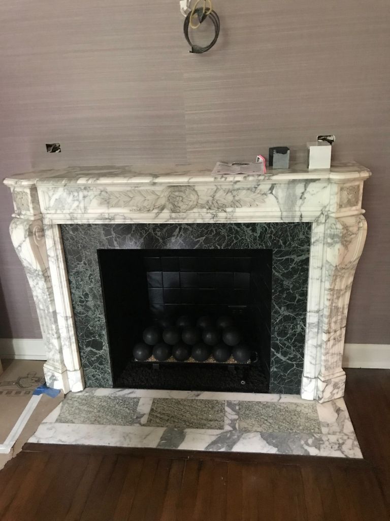 A fireplace with a marble mantle in a living room.