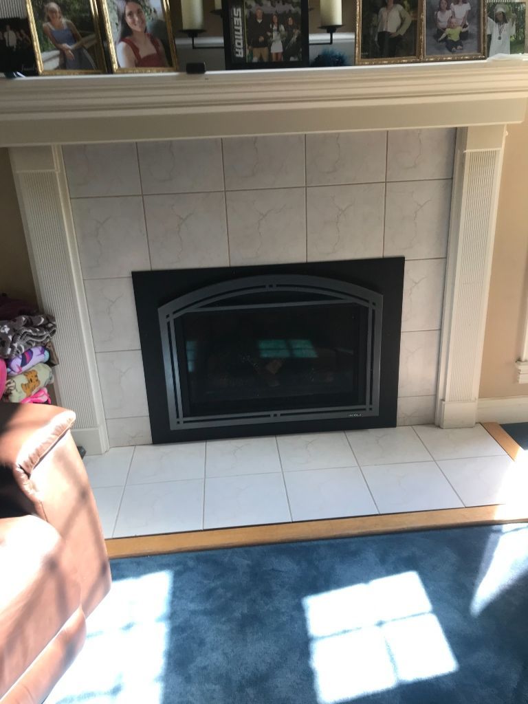 A living room with a fireplace and pictures on the mantle