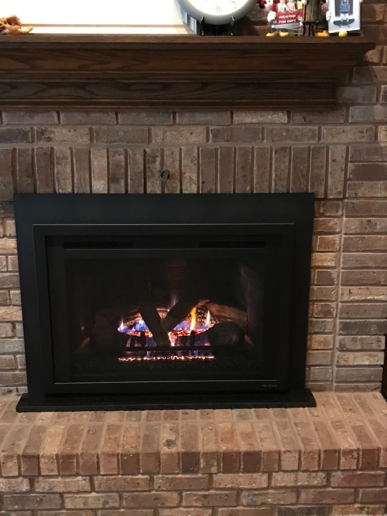 A fireplace with a black frame and a clock on the mantle