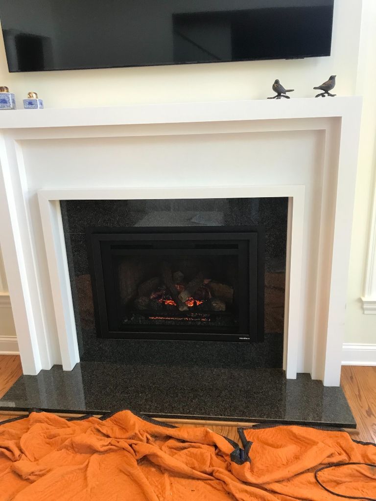 A fireplace in a living room with a flat screen tv above it.