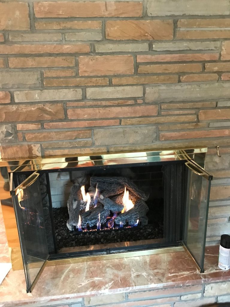 A fireplace with a fire in it and a brick wall behind it.