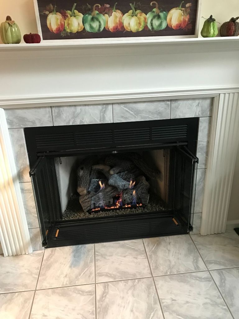 A fireplace in a living room with pumpkins on the mantle.