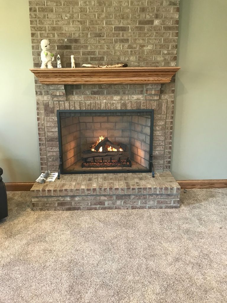 A living room with a brick fireplace and a carpeted floor.