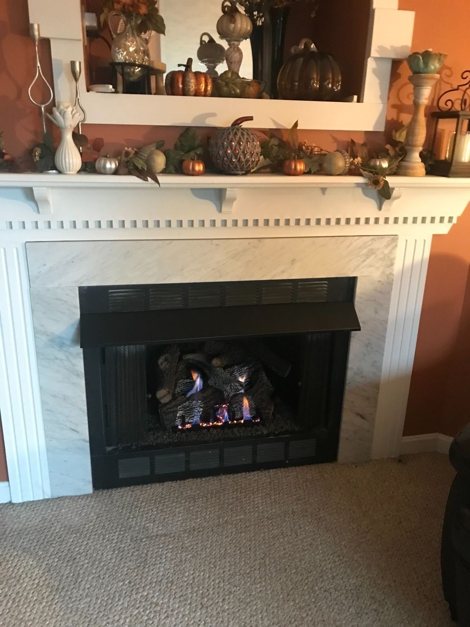 A fireplace in a living room decorated for fall