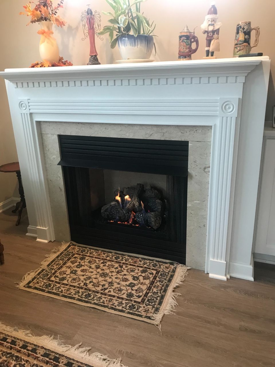 A living room with a fireplace and a rug on the floor.