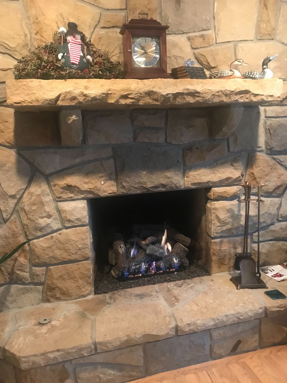A stone fireplace with a clock on the mantle.