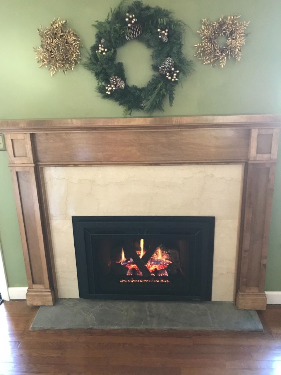 A fireplace with a wreath on the wall above it.