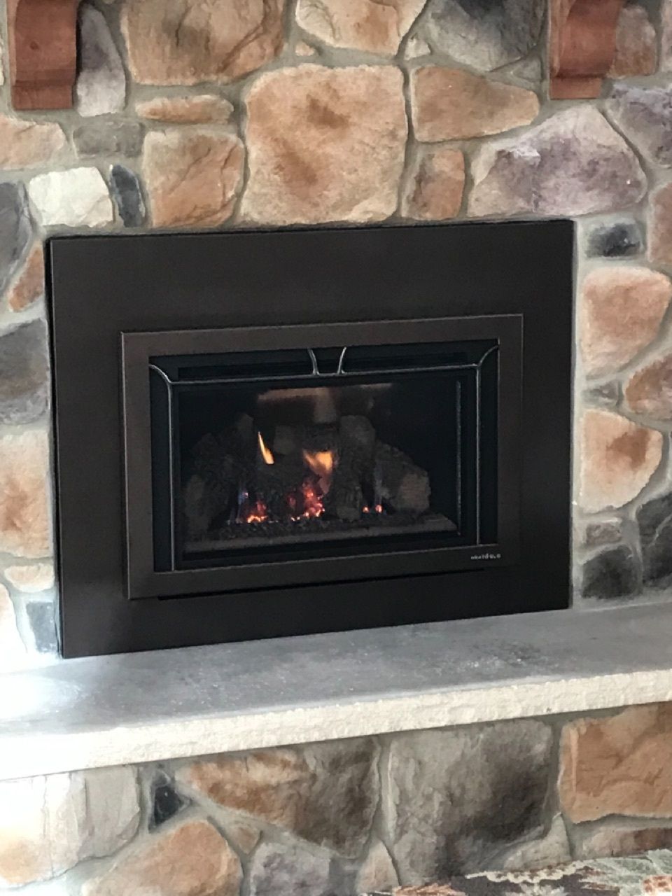 A fireplace with a fire in it is surrounded by a stone wall.
