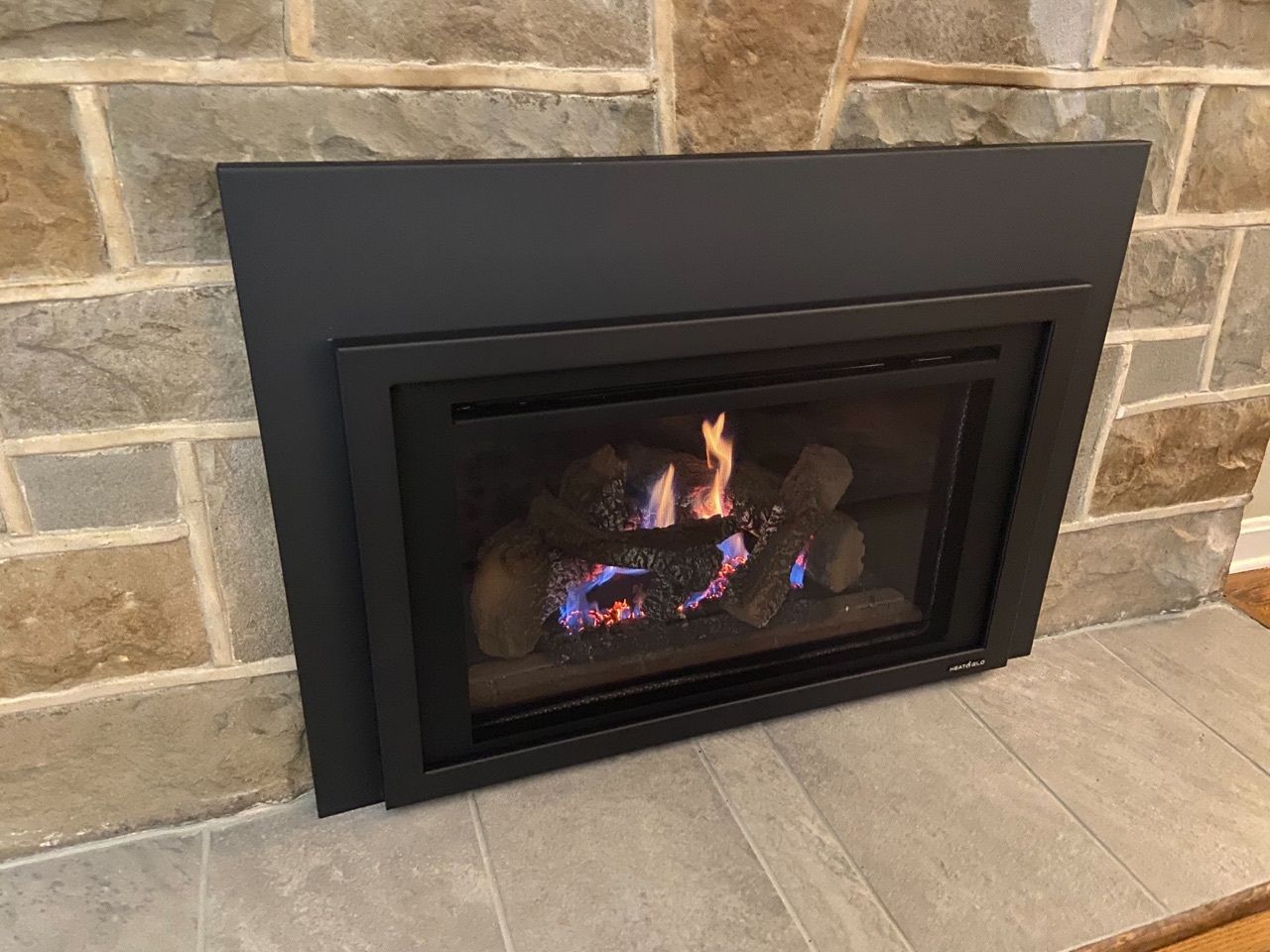 A gas fireplace is built into a stone wall in a living room.