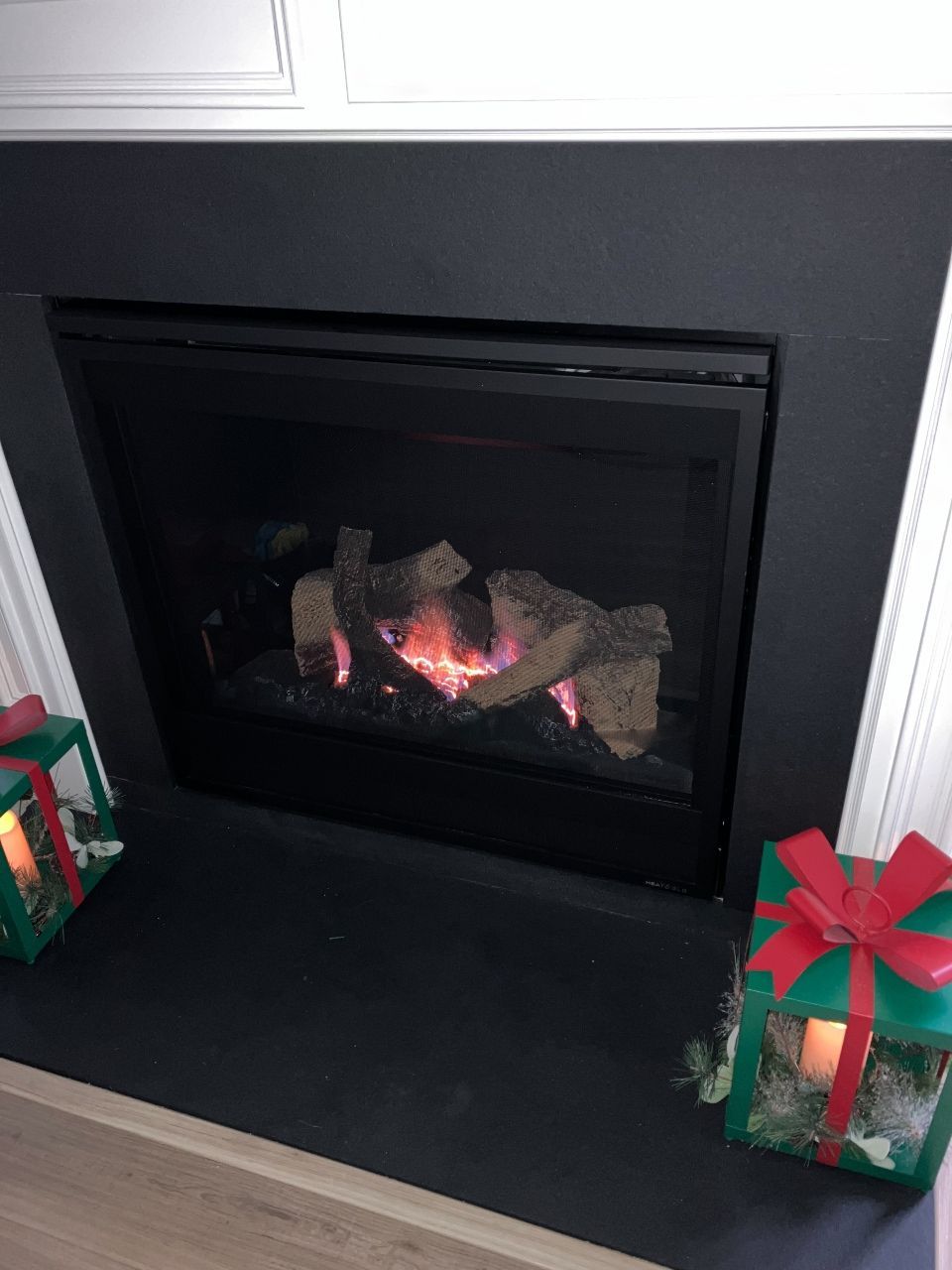 A fireplace with christmas presents in front of it.