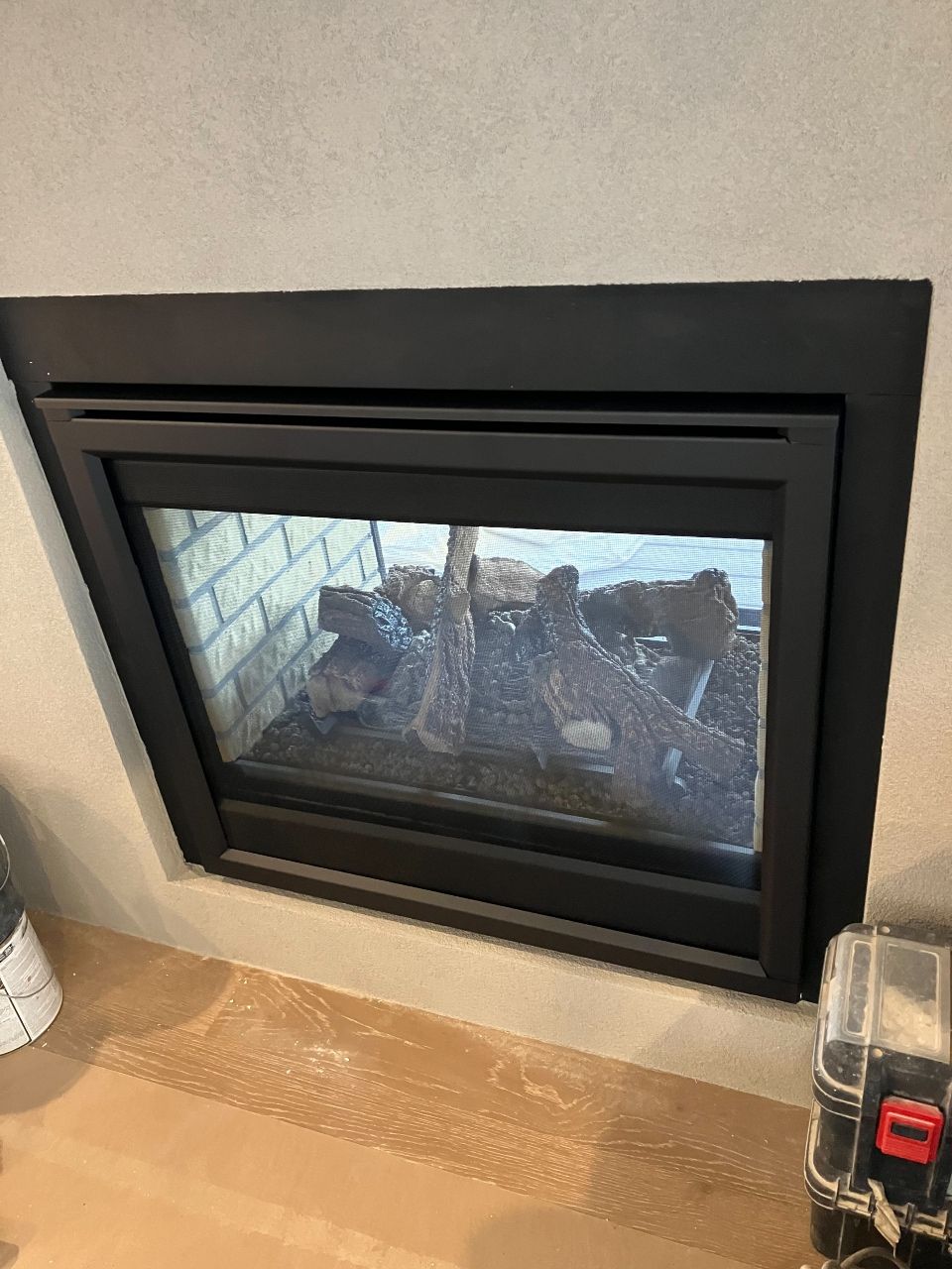 A fireplace with a glass door is being installed in a living room.