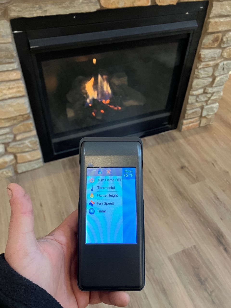 A person holding a cell phone in front of a fireplace