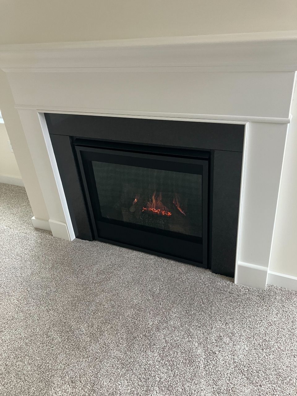 A fireplace is sitting on top of a carpeted floor in a living room.