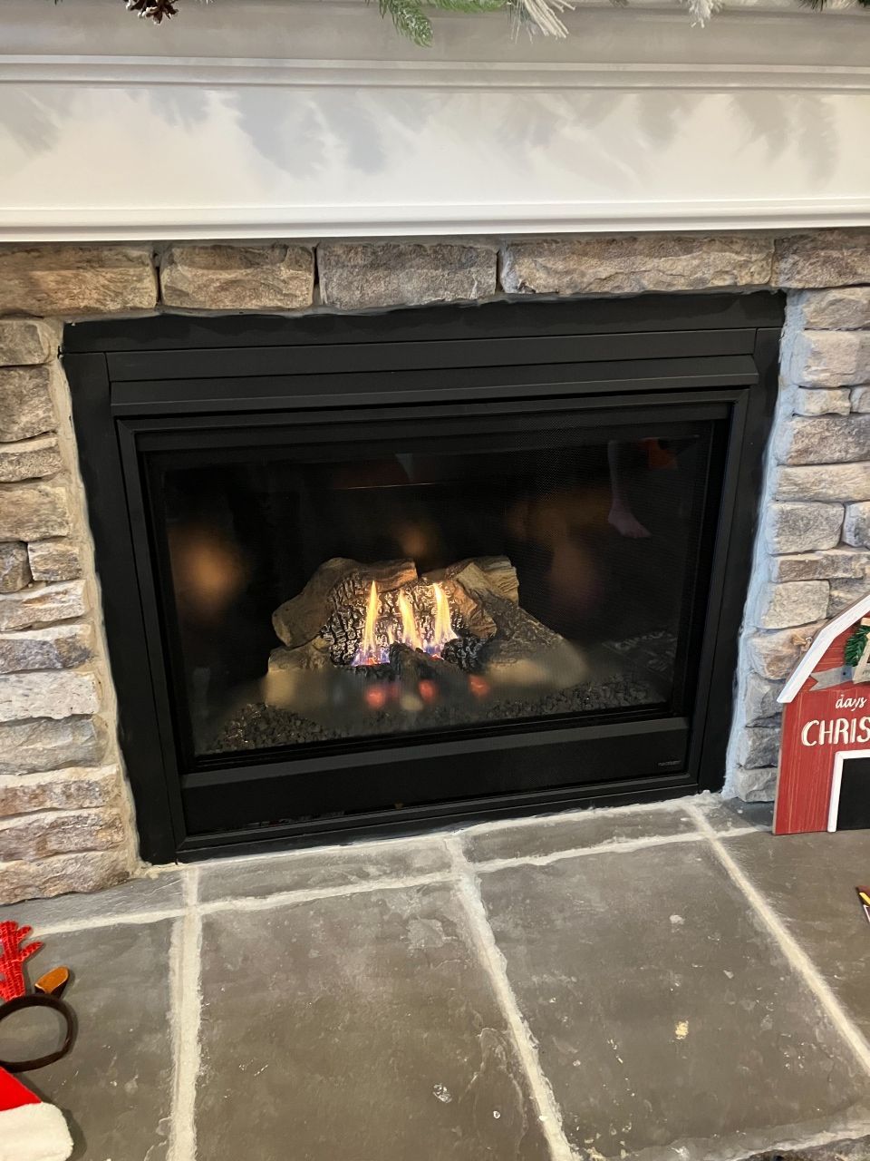 A fireplace with a christmas sign in front of it.