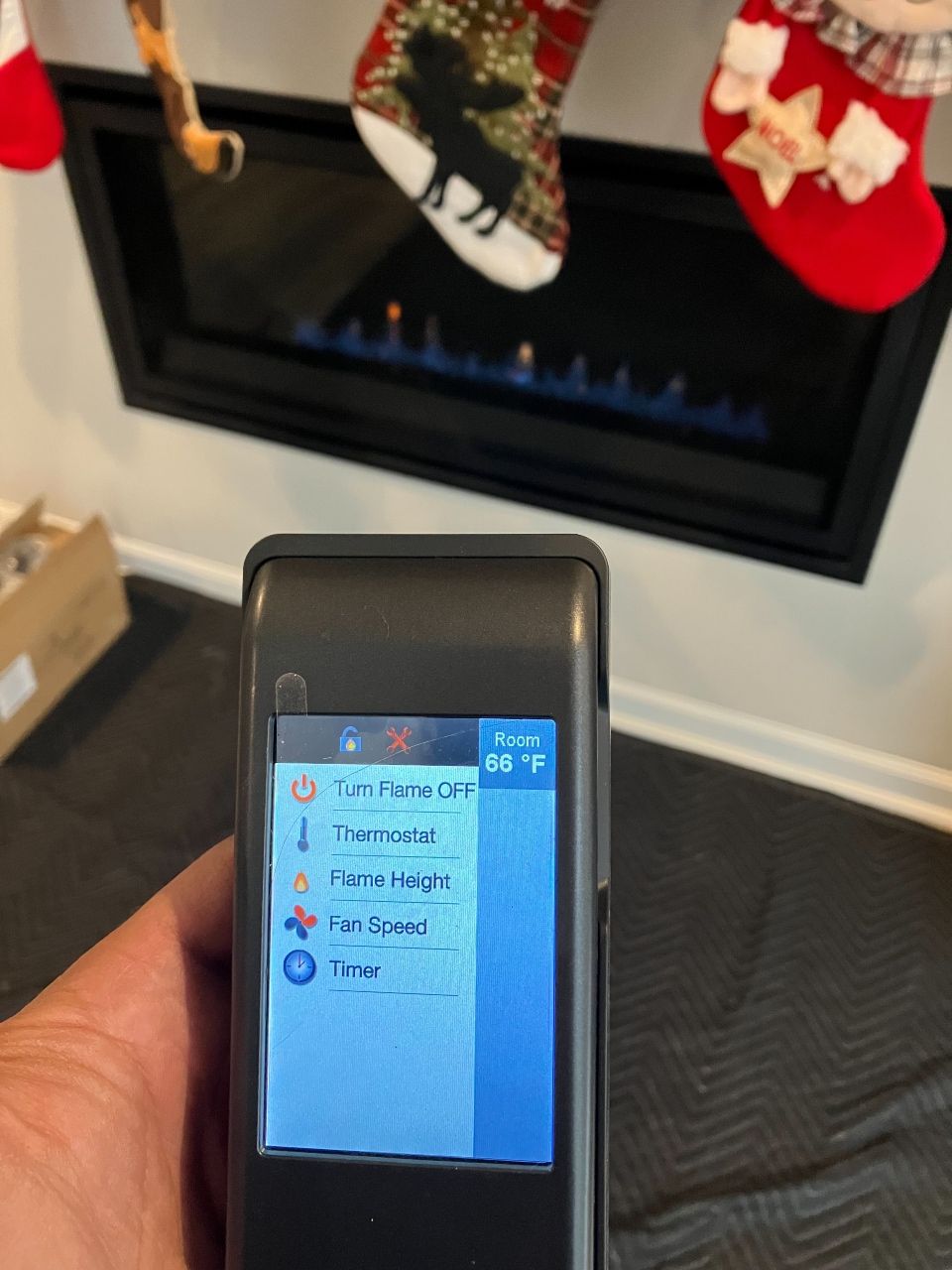 A person is holding a cell phone in front of a fireplace