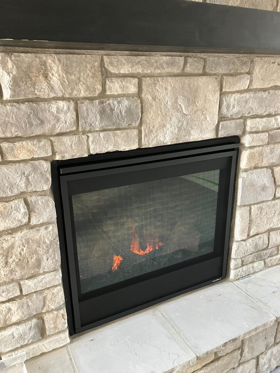 A fireplace with a glass door and a brick wall.