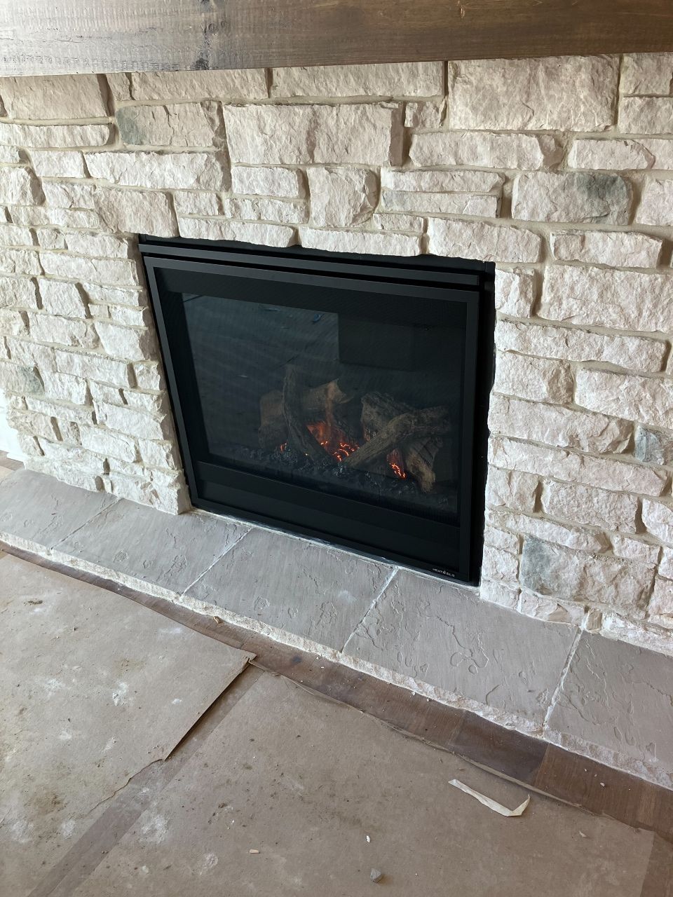 A fireplace with a brick wall and a glass door.