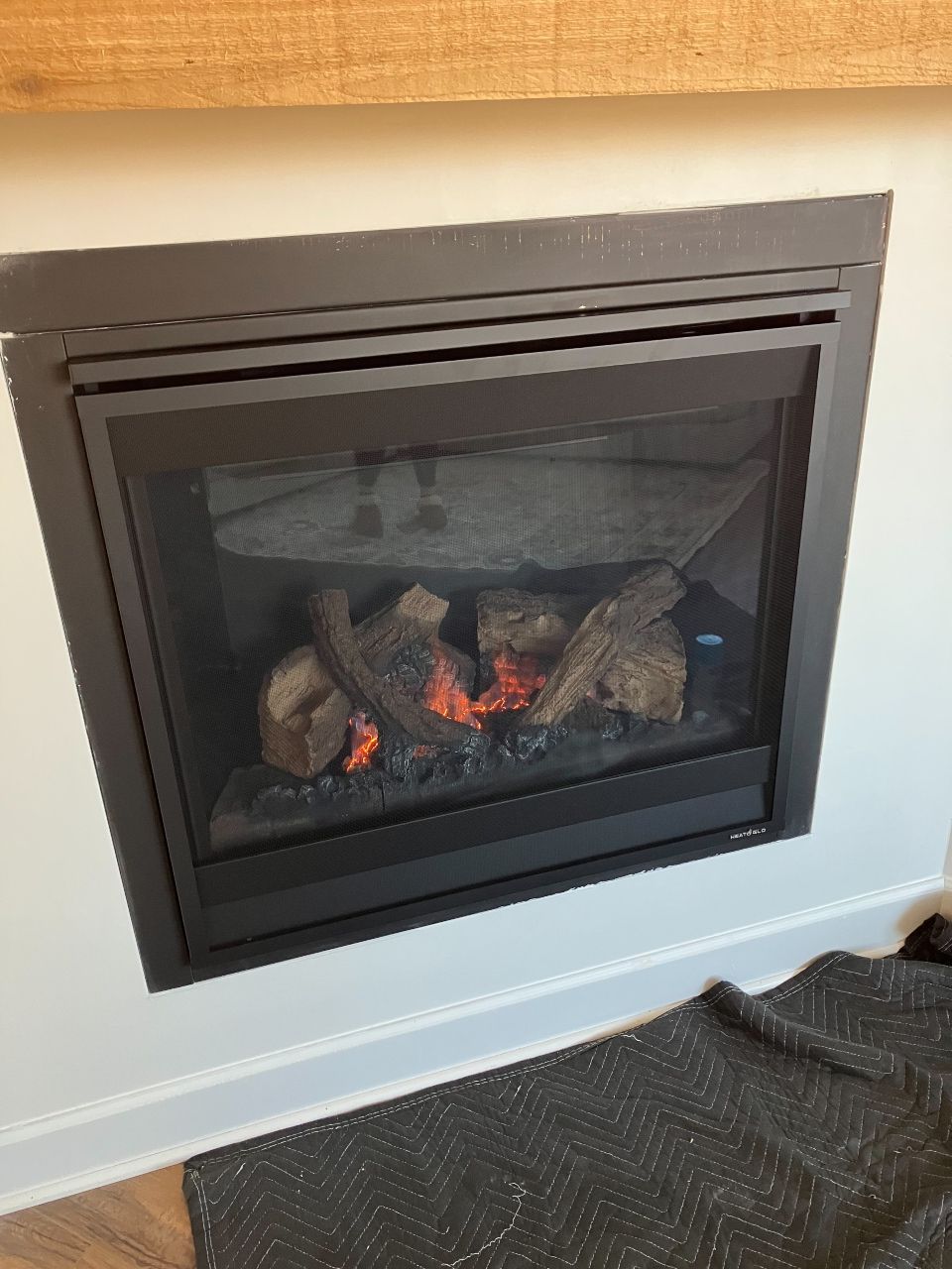 A fireplace with a lot of logs in it is sitting on a rug in a living room.