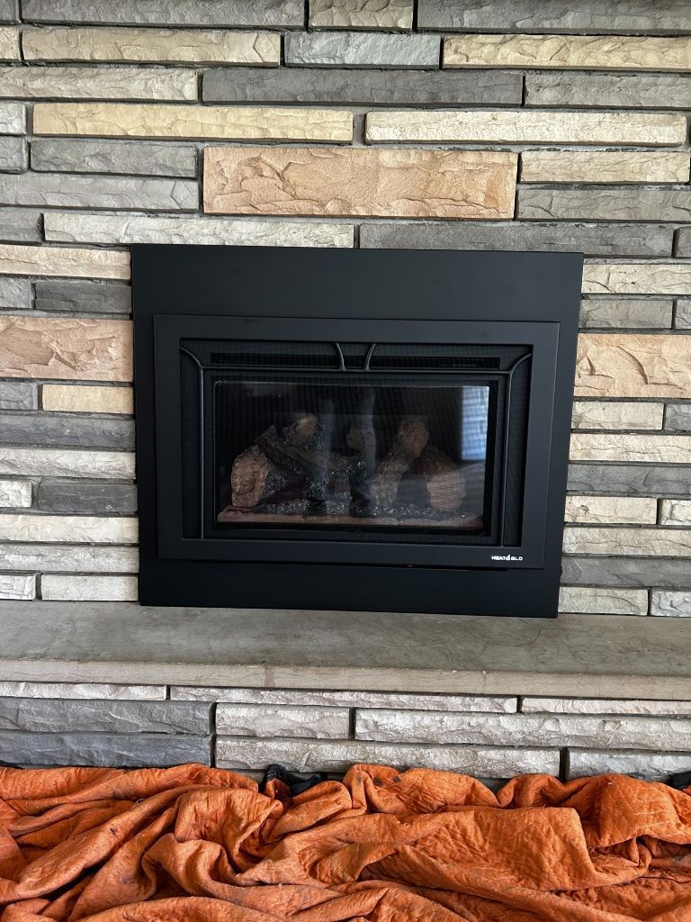 A fireplace with a brick wall and a blanket on the mantle.