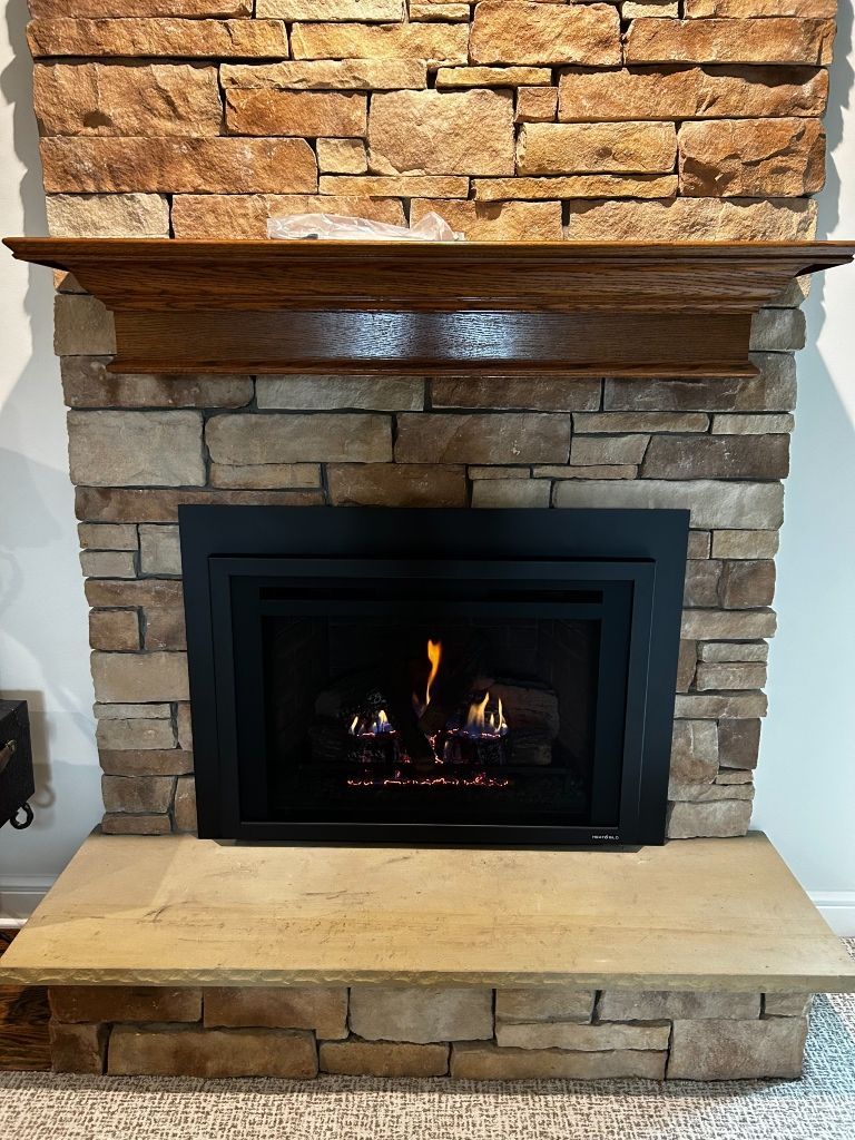 A fireplace with a brick wall and a wooden mantle