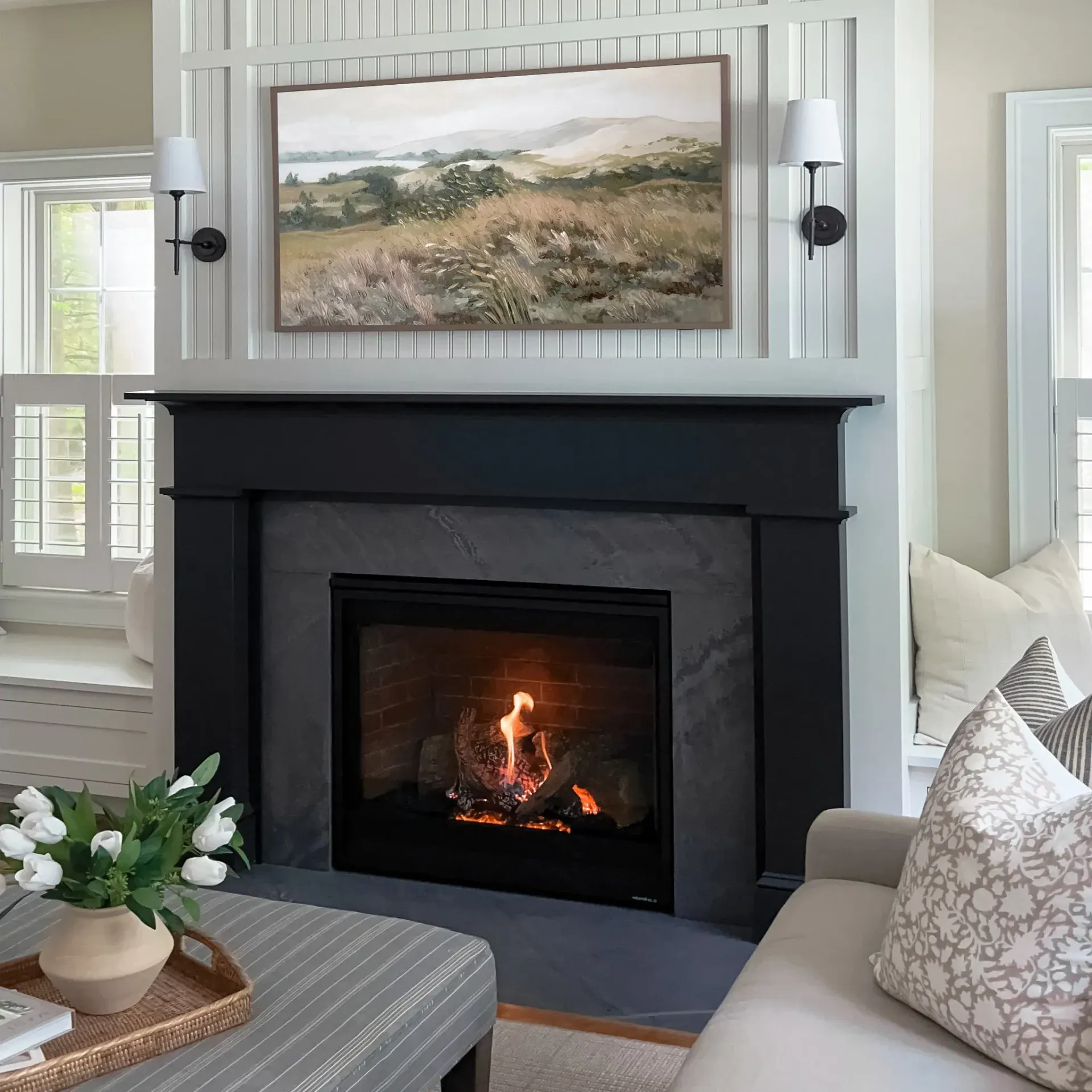 A living room with a fireplace and a painting on the wall above it