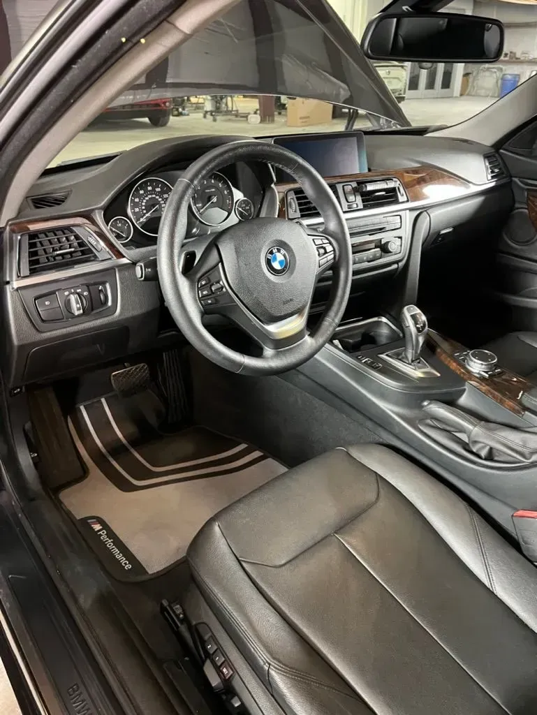 BMW car interior with black leather seats, steering wheel, center console, and sunroof visible