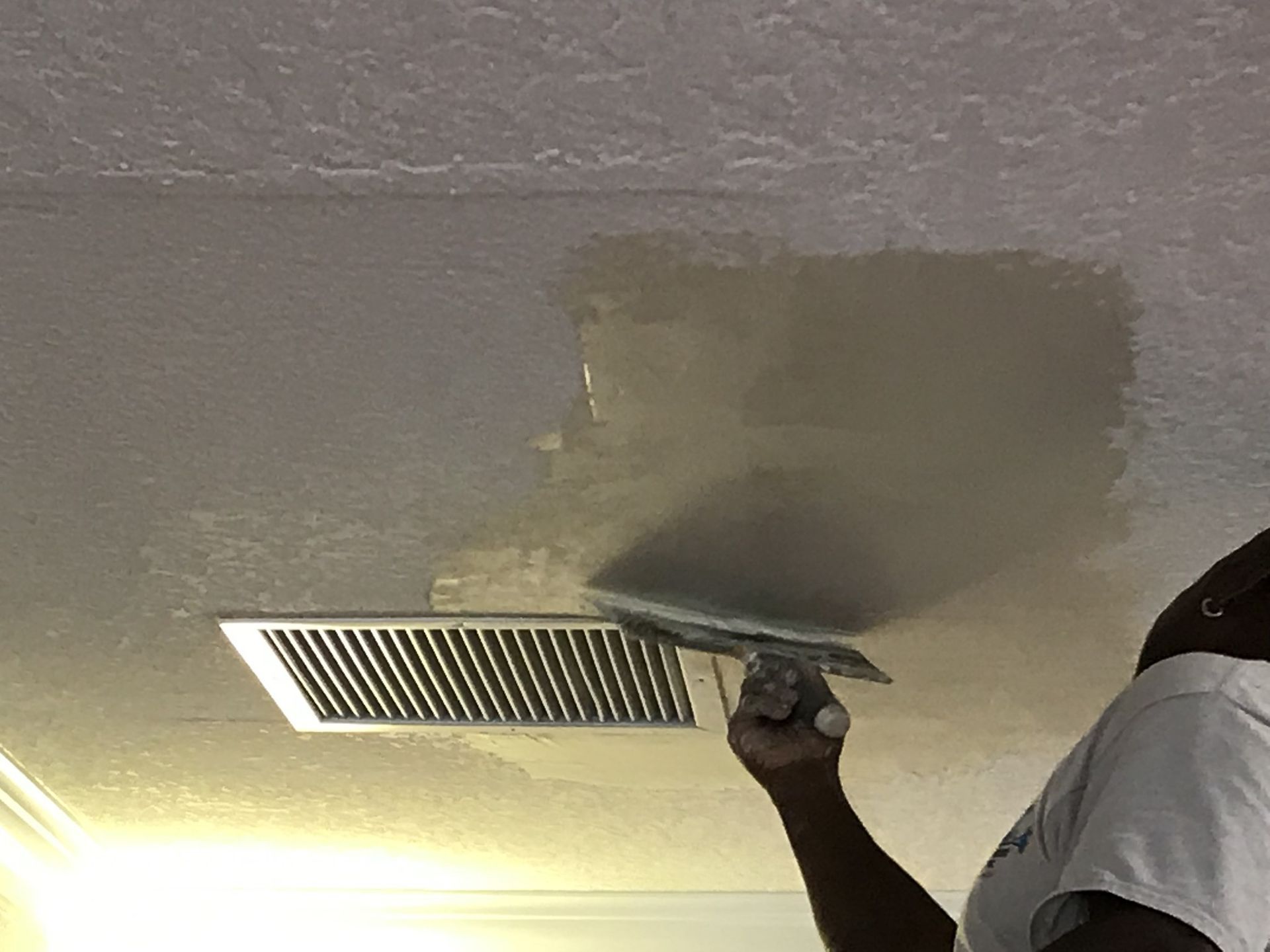 A man is plastering a ceiling with a trowel.