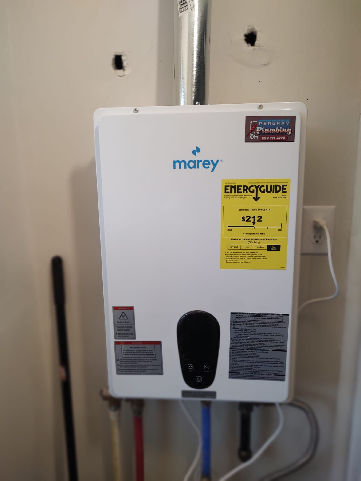 Marey tankless water heater mounted on a white wall, with energy guide sticker and water pipes below.