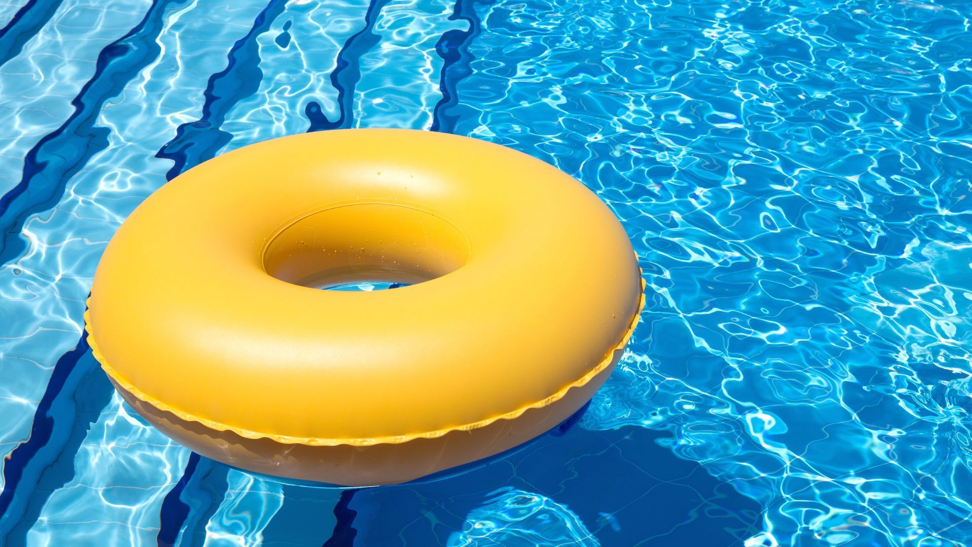 A yellow inflatable ring is floating in a swimming pool.