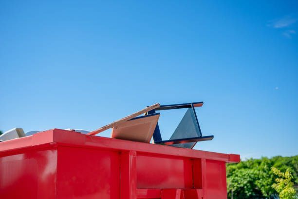 Close-up of a red dumpster filled with furniture and other items.