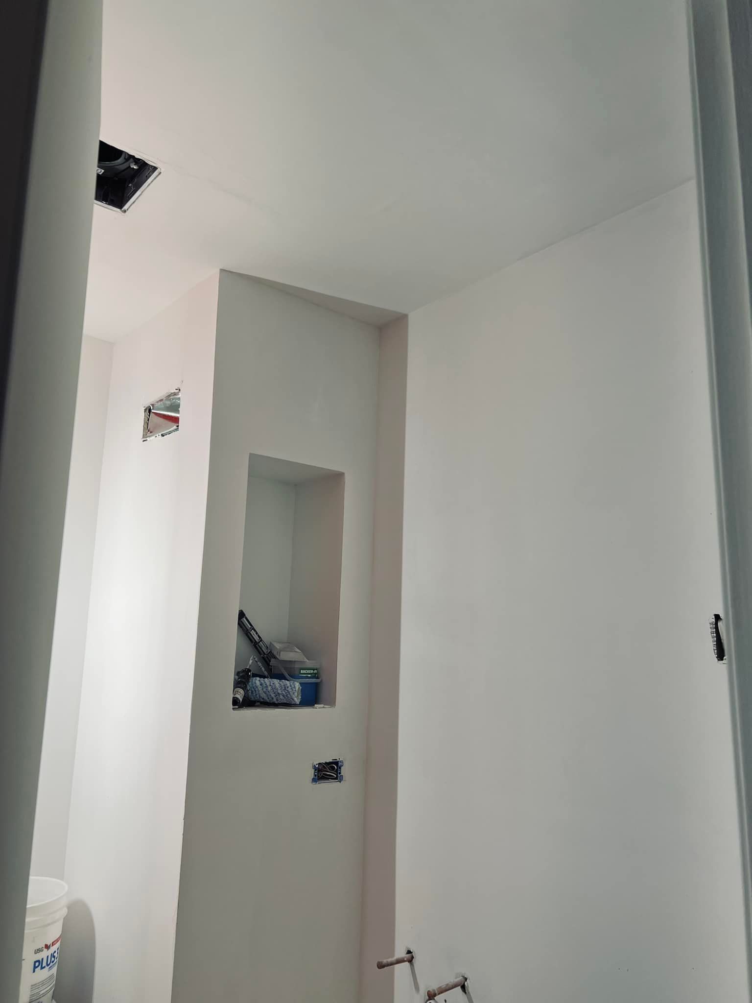 Interior view of a small, white-walled room with a recessed shelf and electrical outlets.