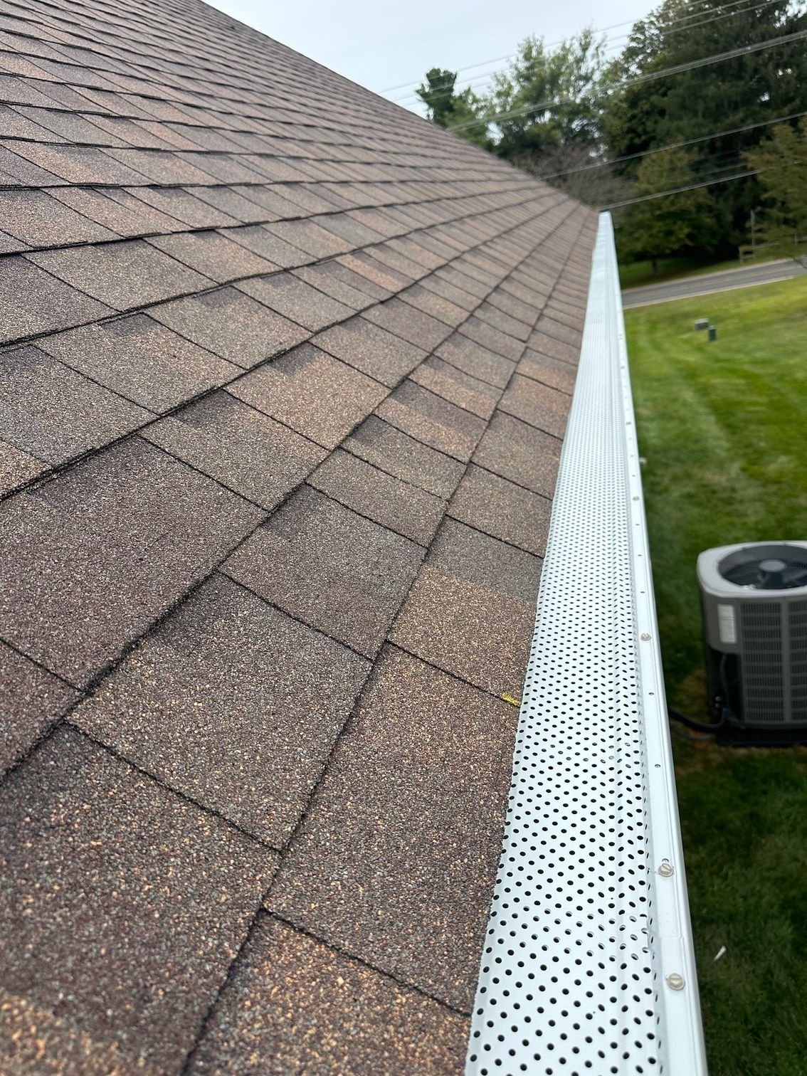 Brown asphalt shingle roof with a gutter guard, viewed from an angle.